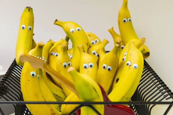 funny pack of yellow bananas with cartoon plastic eyes watching a guitar performance.  performance. Food for children