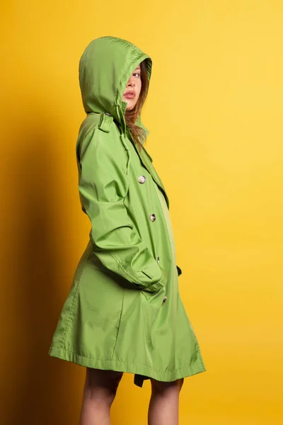 sarı arka planı poz kukuleta ile yeşil muşamba giymiş kadın genç güzel 