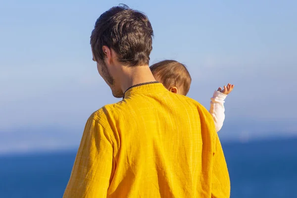 young dad with baby daughter walking along sea