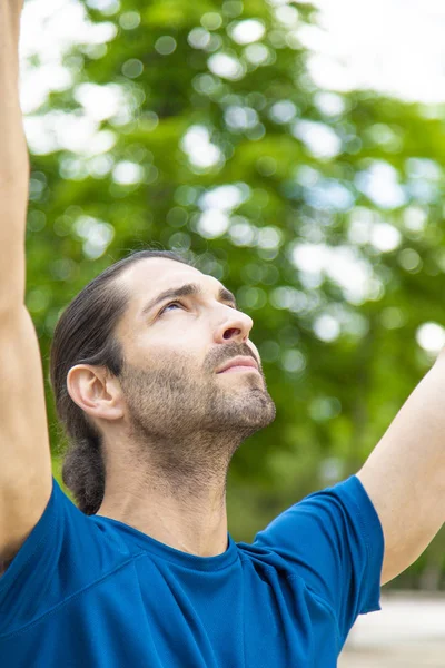 sporty man making pull-up strength exercise in summer park