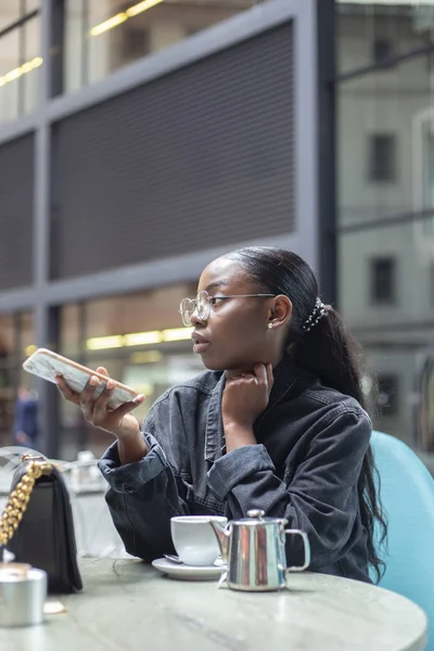 Atractiva Mujer Africana Joven Usando Teléfono Inteligente Mientras Toma Una —  Fotos de Stock