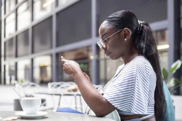 çekici genç Afrikalı kadın terasta çay yaparken Smartphone kullanarak