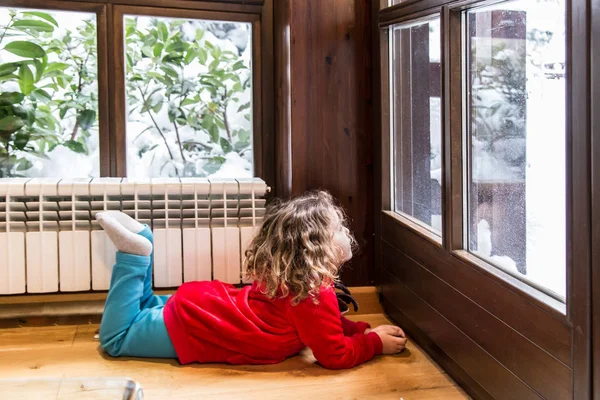 Kış sahne. Küçük kız kırmızı kar pencereden Noel'de bakarak ile giyinmiş