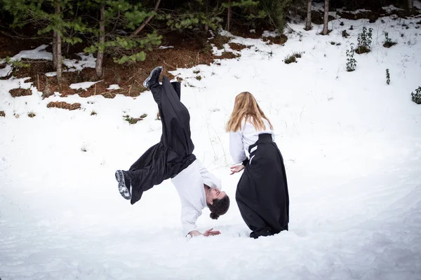 Aikido en la nieve. Mujer y hombre luchando en el bosque —  Fotos de Stock
