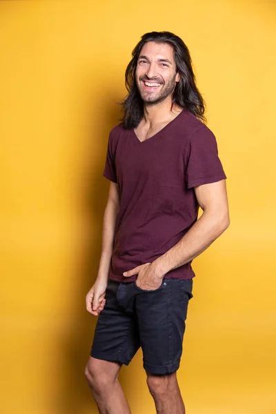 Sarı arka planda gülümseyen adam kameraya gülüyor