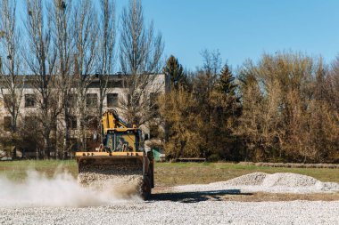 Dneprorudnoe / Ukrayna - Nisan 08 2020: Bir traktör kovadan çakıl döktü