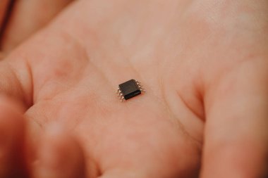 Küçük siyah bir çip bir çocuğun avucunda yatıyor. Salgın bir koronavirüsten sonra insanların yontulması. 