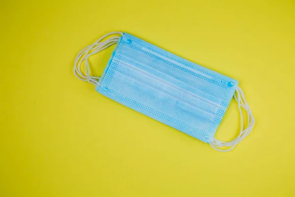 Surgical masks with rubber ear bands on a yellow background. Disposable surgical face mask covers the mouth and nose. The concept of protection against bacteria and viruses.