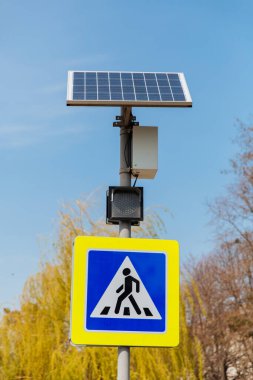 Güneş panellerinden güç alan yaya geçidi tabelası yukarıda. Trafik işaretleri ve kuralları.