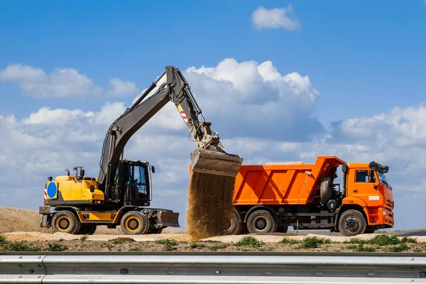 Yellow Backhoe Loader Loads Earth Truck Construction Road Blue Sky — Stock Photo, Image