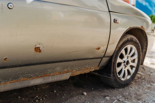 Paslı ve metal aşınmalı bir araba kapısı. Pas lekeleri. Tamire ve yol tuzuna ihtiyacım var..