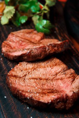 Kızarmış fileto bifteğinin kalın sulu porsiyonları eski ahşap bir tahtaya tuz serpiştirilir. Yemek servise hazır..