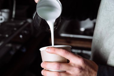 Kahveci kahveye sıcak süt koyar. Barista cappuccino yapıyor, barmen kahve hazırlıyor. Uzaklaştır