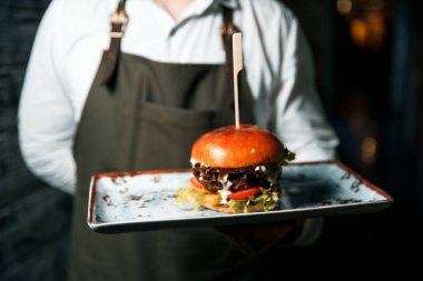 Taze lezzetli hamburger, servis etmeye hazır tabakta yatıyor..