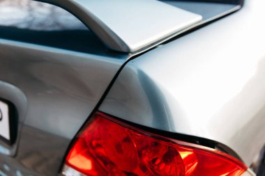 Bir arabanın arka lambası kırık. Mavi yolcu vagonu. Arka çamurlukta çizik var. Trafik kazası..