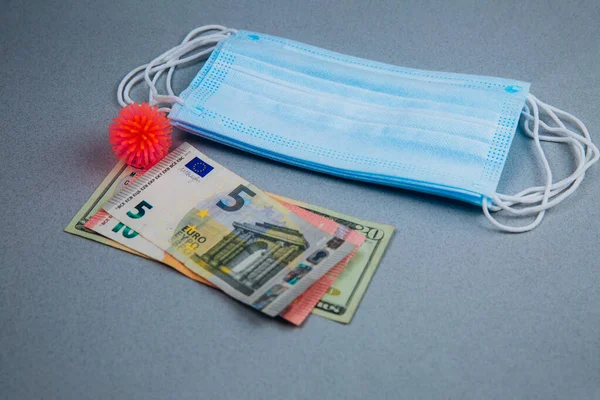 Tıbbi maske, soyut virüs modeli ve gri arka planda para, dünya koronavirüs salgını ve ekonomik hasar. Corona virüsü konsepti.