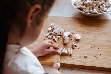 Tahtada taze şampiyon mantarları. Kız mantarları bıçakla kesiyor..