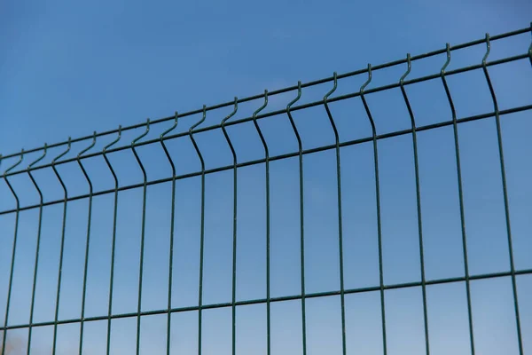Steel grill fence with wire against the blue sky.