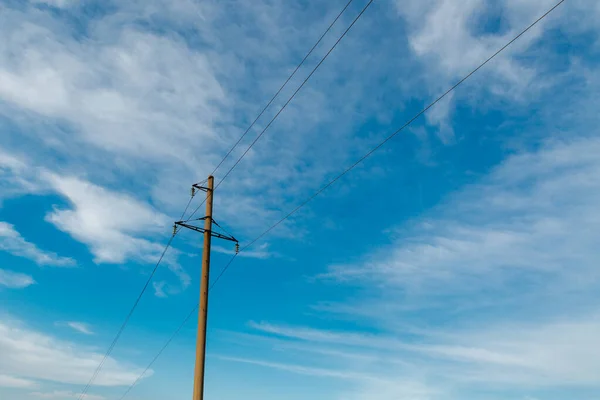  Elektrik kablolarıyla elektrik direği beyaz bulutlu, berrak bir gökyüzüne karşı. Elektrik iletim hattı, güç kaynağı