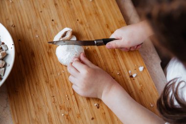 Tahtada taze şampiyon mantarları. Kız mantarları bıçakla kesiyor..