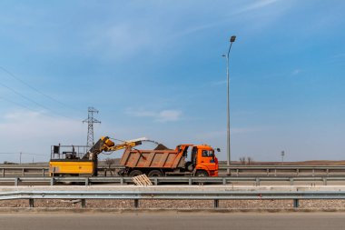 Yol çalışıyor. Asfalt kaldırma makinesi kamyona toz asfalt yükleme.