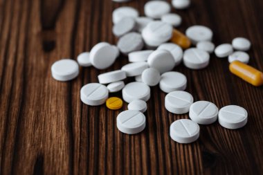 Beyaz ve sarı haplar, tabletler, tahta arka planda kapsüller. Fotokopi alanı ile sağlık hizmeti kavramı