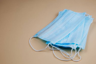 Bej arka planda tıbbi koruyucu maske. Tek kullanımlık yüz maskesi ağız ve burnu kapatır. Bakteri ve virüslere karşı koruma kavramı.