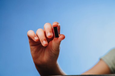 Bir kız elinde tutuyor ve küçük siyah bir çipi inceliyor. Salgın bir koronavirüsten sonra insanların yontulması. Boşluğu kopyala