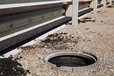 Şehir caddesinde yürüyen insanlar için tehlike arz eden açık bir kanalizasyon kapağı. Rögar kapağı yok. Onarım işi