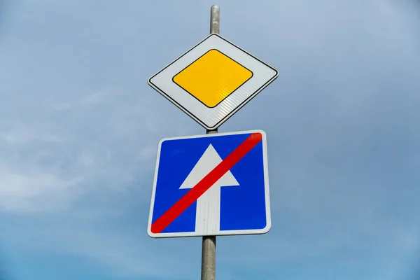 Road sign main road and one-way road end sign on blue sky background.