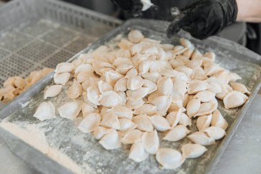 Eldivenli bir aşçı köfte heykeli yapar. Hamur köfteleri, un serpiştirilmiş demir bir tepside yatıyor..