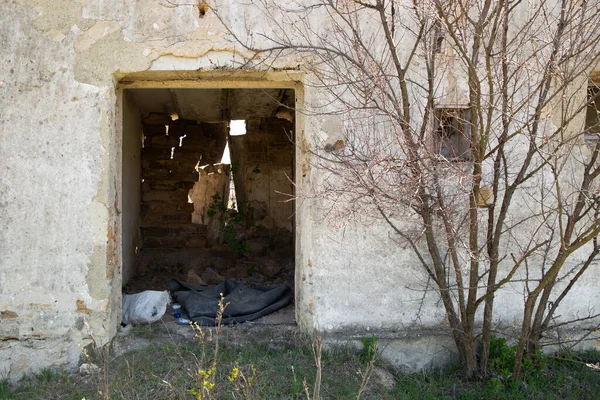 Ruined, abandoned building. Near the building there is a cloth and a part of the wall — Stock Photo, Image