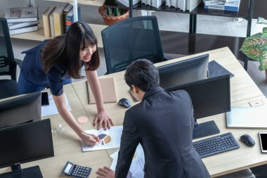 A man is explaining work to a girl at the desk.