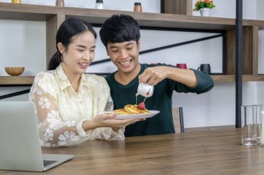 Gençler çilekli turtanın üzerine bal döküyorlar..