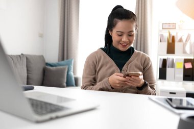 Genç Asyalı kadın iletişim için cep telefonu kullanıyor.