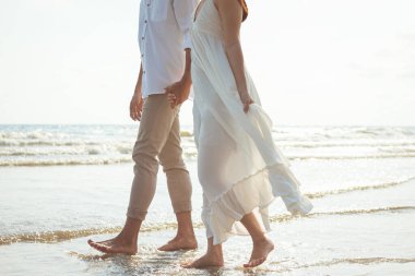 Kumsalda el ele tutuşan çift. Sahilde romantik bir çift