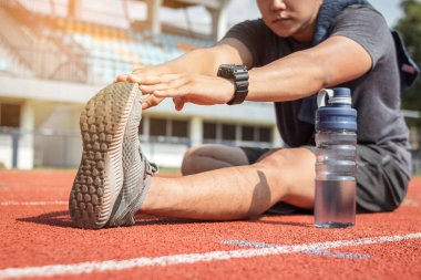 Koşucu bacaklarını açıyor. Koşu antrenmanına hazırlanıyor..