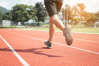 Koşucu erkek bacakları stadyumdaki yarış pistinde koşuyor..