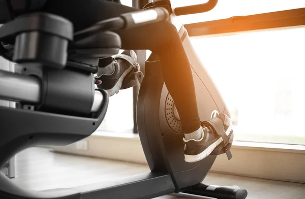 Legs of woman biking in gym, exercising legs doing cardio workout cycling bikes.