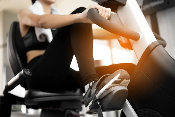 Legs of woman biking in gym, exercising legs doing cardio workout cycling bikes.