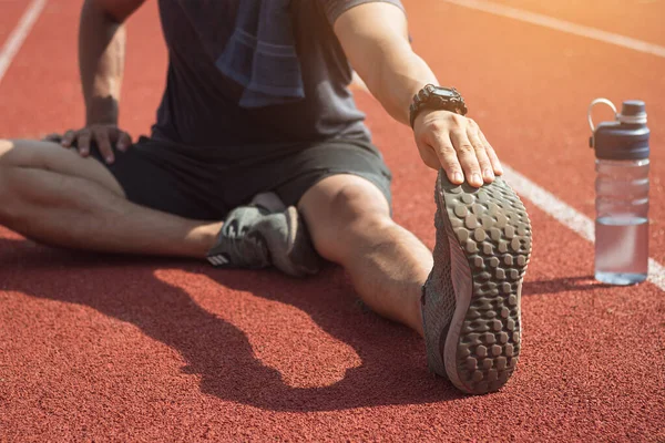 Koşucu bacaklarını açıyor. Koşu antrenmanına hazırlanıyor..