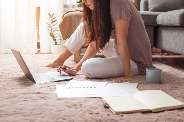 Evde çalışmak için dizüstü bilgisayar kullanan genç bir kadın.