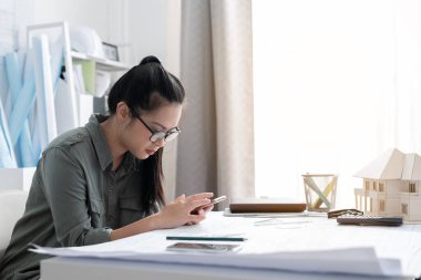 Mimari modelli cep telefonu kullanan mimar kadın.