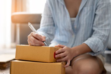 Küçük işletme sahibi kadın çevrimiçi sipariş için müşteriye göndermek üzere bilgi adresi ürünü yazıyor