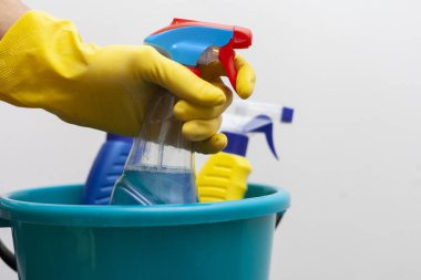 Temizlik konsepti. Ev işi plastik aksesuarlar. Eldivenli kadın ya da erkek temizlik için özel sprey kullanıyor. Kimyasal deterjan şişesi. Deterjanla temizleyip yıkamak..
