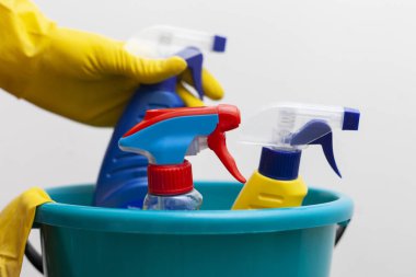 Temizlik konsepti. Ev işi plastik aksesuarlar. Eldivenli kadın ya da erkek temizlik için özel sprey kullanıyor. Kimyasal deterjan şişesi. Deterjanla temizleyip yıkamak..