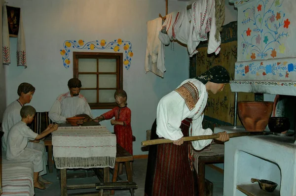 Oyuncak bebekler (karı, koca, iki çocuk) mutfakta geleneksel kostümlerle ve bir Rus sobasıyla