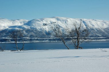 Kış manzarası: dağ gölü ve kardaki yamaçlar