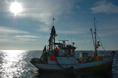 Contra ışığında küçük bir balıkçı teknesi (çerçevedeki güneş))