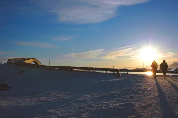 Akşam manzarası: güneş batarken, yolda yürüyen iki insan.